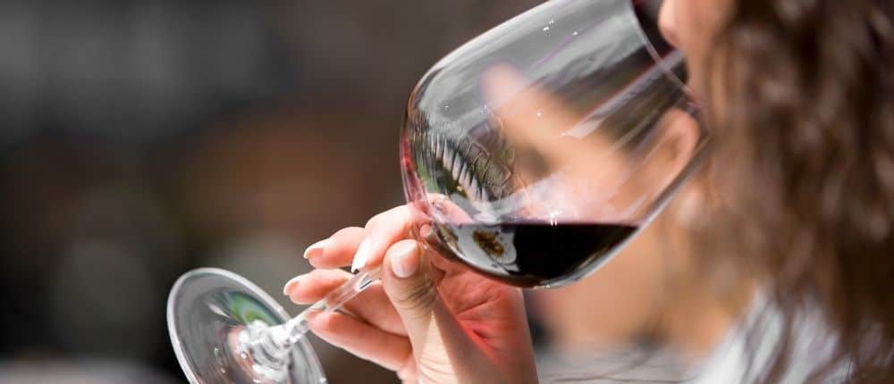 Close-up of someone drinking red wine from a large glass