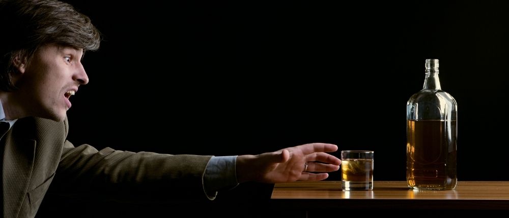 How to stop alcohol cravings - image of a man reaching for an alcoholic drink
