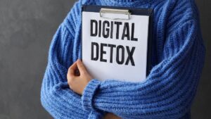 Why we are closing the Club Soda Facebook group - picture of a person in a blue jumper holding a clip board with the words "digital detox"